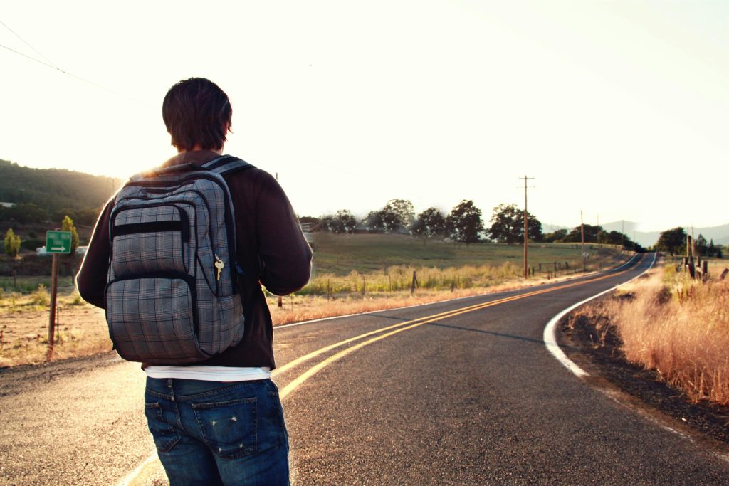 Persona con mochila caminando por una carretera rural al amanecer, con el paisaje natural de fondo y la carretera extendiéndose hacia el horizonte, representando el camino laboral en relación al tema de la mochila austriaca.